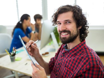 Male graphic designer writing on a document in office